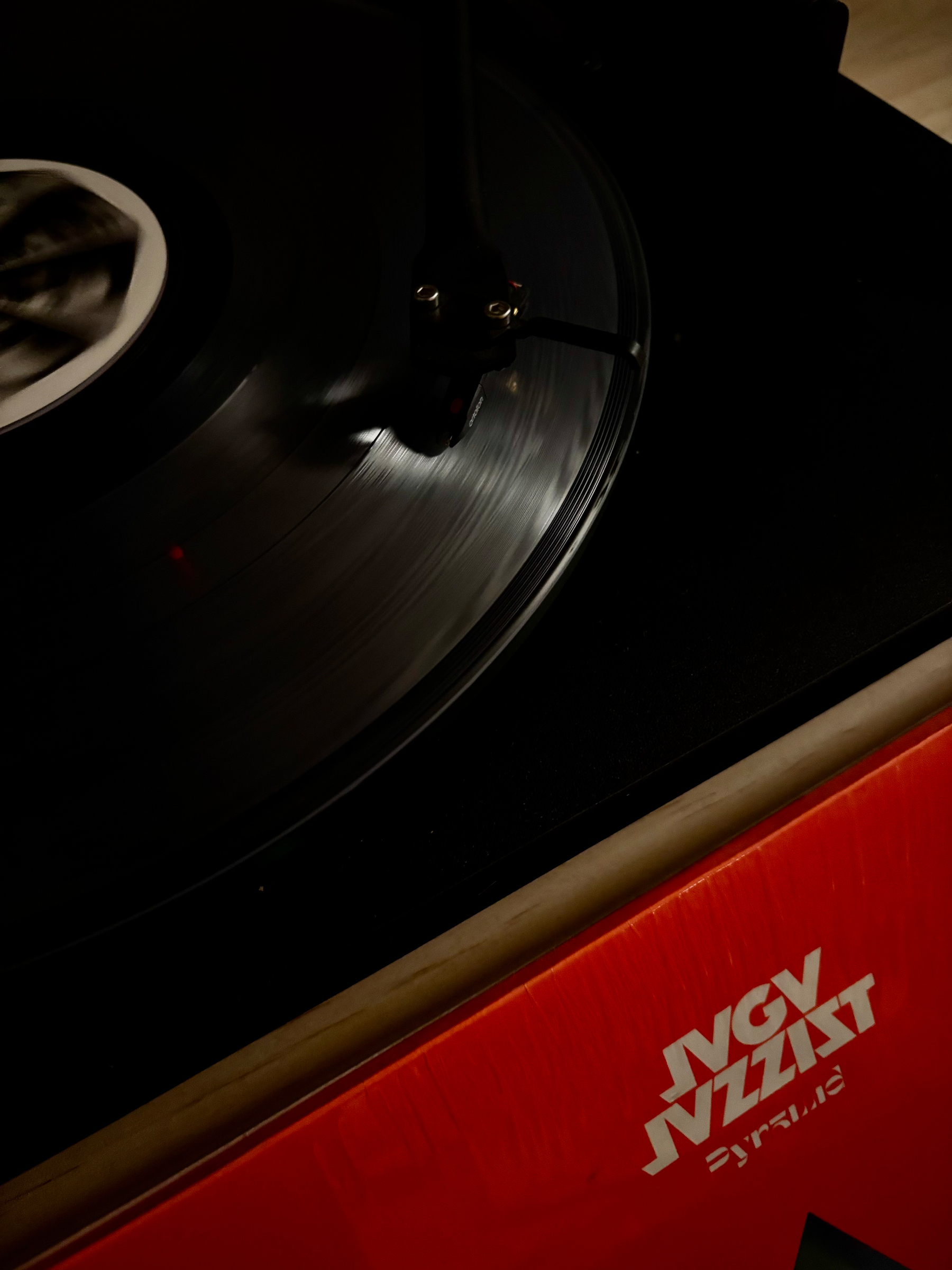 En vinylplate spiller på en platespiller, i forkant et rødt plateomslag der det står JAGA JAZZIST.