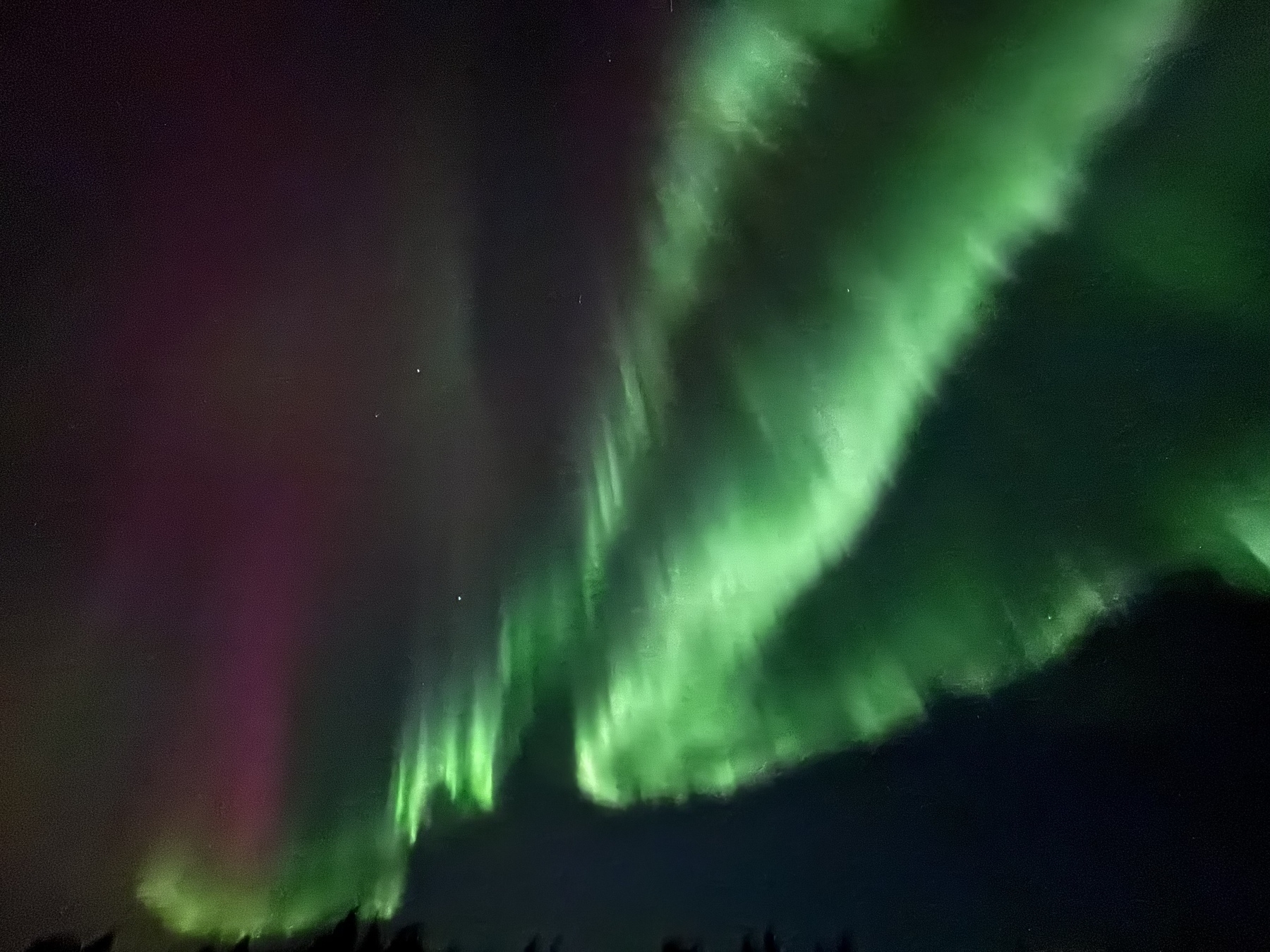 Vibrant green and purple auroras illuminate the night sky.